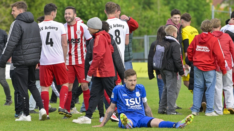 Ziemlich bedröppelt saß Weigenheims Kapitän Florian Eisenhut am letzten Spieltag 25/26 nach dem Schlusspfiff auf dem Rasen. Hinter ihm jubeln die Arberger, die 2:1 gewannen und so noch Platz 2 erklommen. (Foto: Martin Rügner)