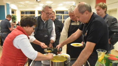 Hauswirtschaftsmeisterin Renate Ixmeier schöpft unter den Augen von Allianzmanager Martin von Loeffelholz (rechts) die Kürbissuppe in die Teller. Oberscheinfelds Bürgermeister Peter Sendner (Zweiter von links) und sein Schlüsselfelder Amtskollege Johannes Krapp (Zweiter von rechts) sorgen mit Kürbiskernen und Kürbisöl für den letzten Feinschliff. Die anderen Bürgermeister – im Foto Armin Luther aus Burghaslach und Reinhard Streng aus Langenfeld (Dritter und Vierter von links) – servieren den Feuerwehrkommandanten. (Foto: Andreas Reum)