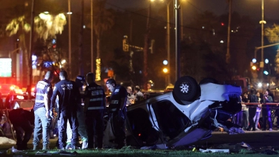 Polizei und der Rettungsdienst stehen nahe des Strands von Tel Aviv neben dem Auto, das sich überschlagen hat. (Foto: Oren Ziv/AP/dpa)