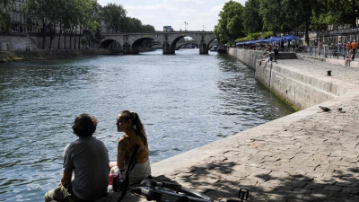 Zwei junge Leute sitzen am Ufer der Seine in Paris. (Foto: Alain Jocard/AFP/dpa)