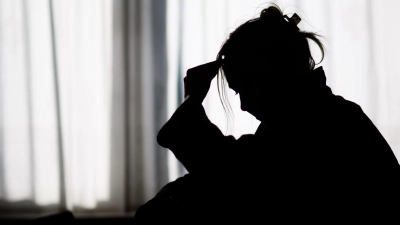 Silhouette einer Frau vor einer hellen Fensterfront (Foto: Julian Stratenschulte/dpa)