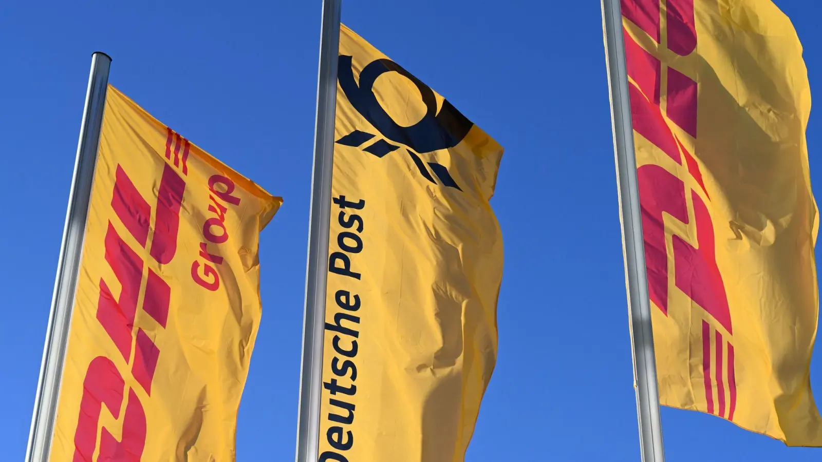 Eine Deutsche-Post-Fahne an der Konzernzentrale, umrahmt von DHL-Fahnen. (Foto: Wolf von Dewitz/dpa)