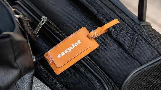 Ein Adressanhänger mit dem Logo von Easyjet ist an einem Koffer am BER befestigt. Das Unternehmen stellt seine Jahreszahlen vor. (Foto: Paul Zinken/dpa)