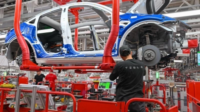 Ein Mitarbeiter der Tesla Gigafactory in Brandenburg. Der Autobauer hat dem Land ein starkes Wachstum beschert. (Foto: Patrick Pleul/dpa)