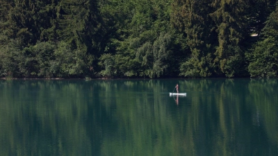 Eine Frau paddelt auf einem Stand-up Paddle Board über den Forggensee.  (Foto: Karl-Josef Hildenbrand/dpa)