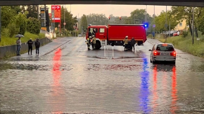 Ein Einsatzfahrzeug der Feuerwehr sichert eine mit Regenwasser vollgelaufene Unterführung ab. (Foto: Ferdinand Merzbach/News5/dpa)