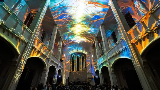 Laserprojektionen sind zum Start der Lichtshow „Genesis“ in der St. Markus-Kirche zu sehen. (Foto: Lennart Preiss/dpa)