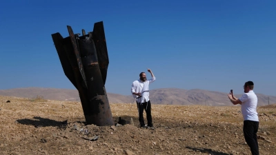 Menschen neben dem Wrack einer iranischen Rakete, die im Westjordanland eingeschlagen ist.  (Foto: Mahmoud Illean/AP/dpa)