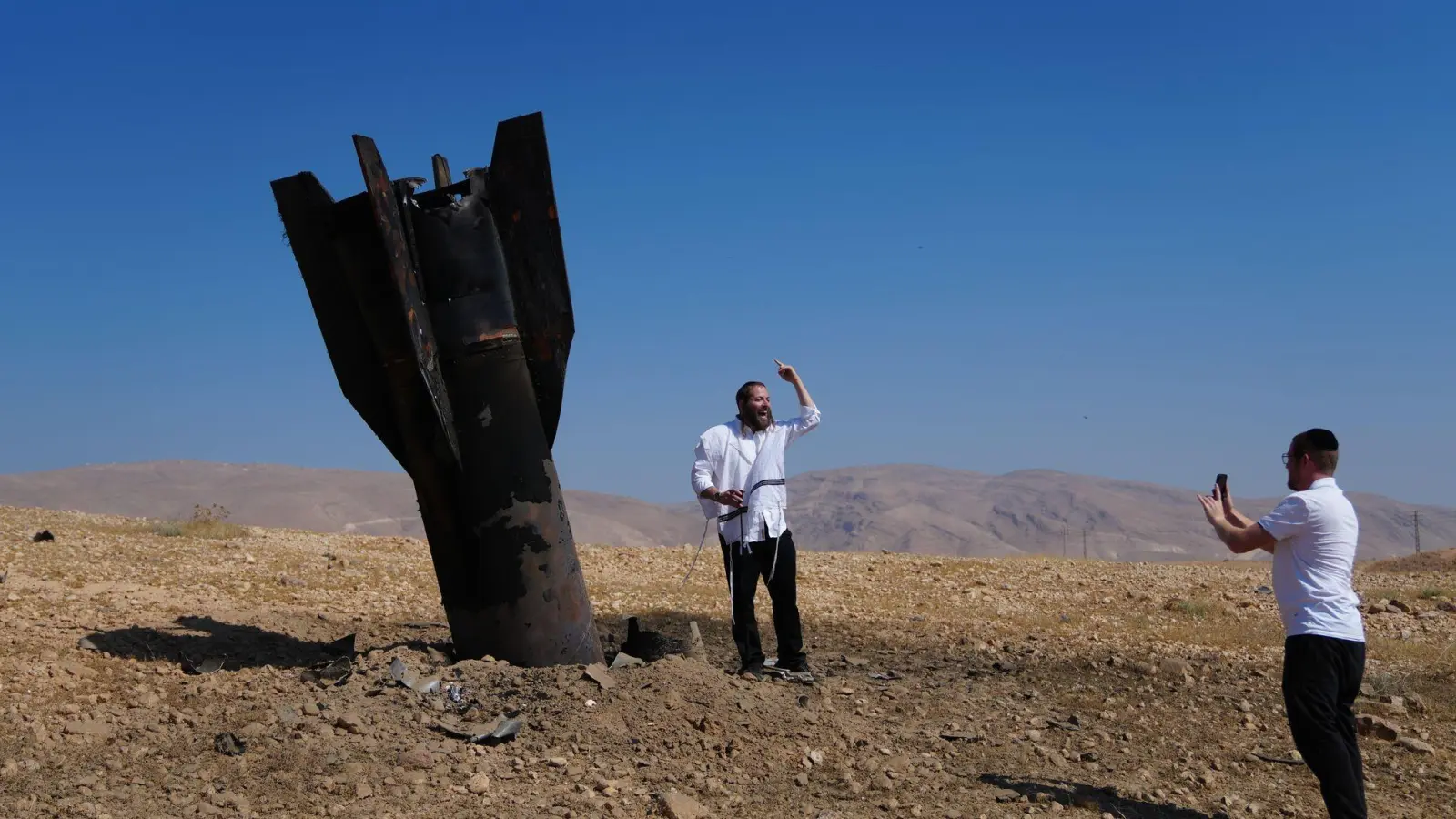 Menschen neben dem Wrack einer iranischen Rakete, die im Westjordanland eingeschlagen ist.  (Foto: Mahmoud Illean/AP/dpa)