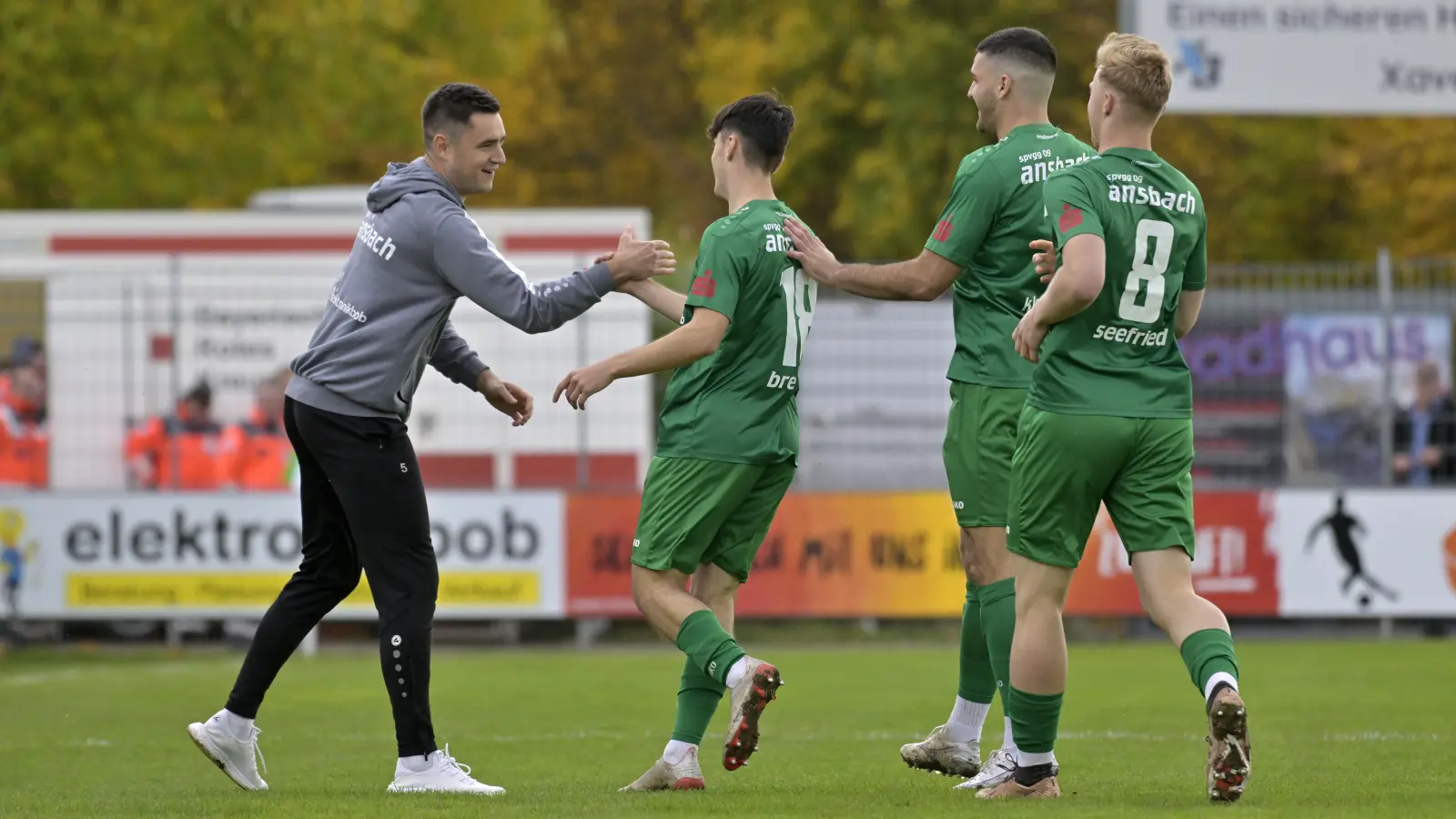„Das gewinnen wir heute für dich”: Ansbachs Pepe Brekner klatscht nach seinem 1:0 mit Trainer Christoph Hasselmeier ab. Michael Kleinschrodt und Niklas Seefried (Nummer 8) freuen sich auch mit. (Foto: Martin Rügner)