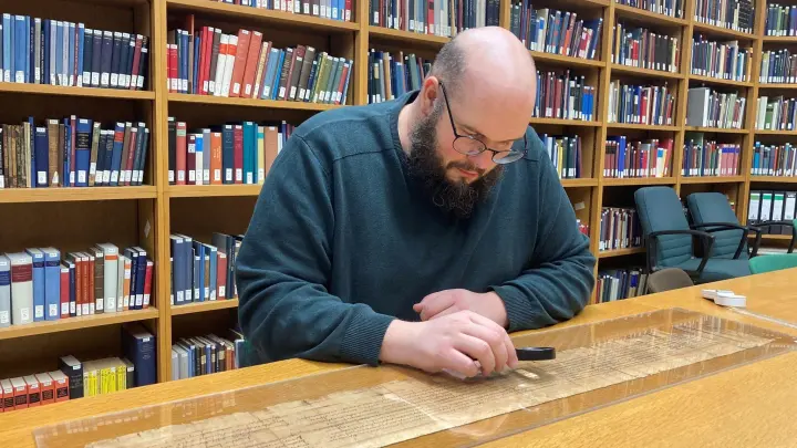 Der Papyrologie-Junior-Professor Patrick Reinard studiert den Text einer Papyrus-Rolle an der Universität Trier. (Foto: Birgit Reichert/dpa)