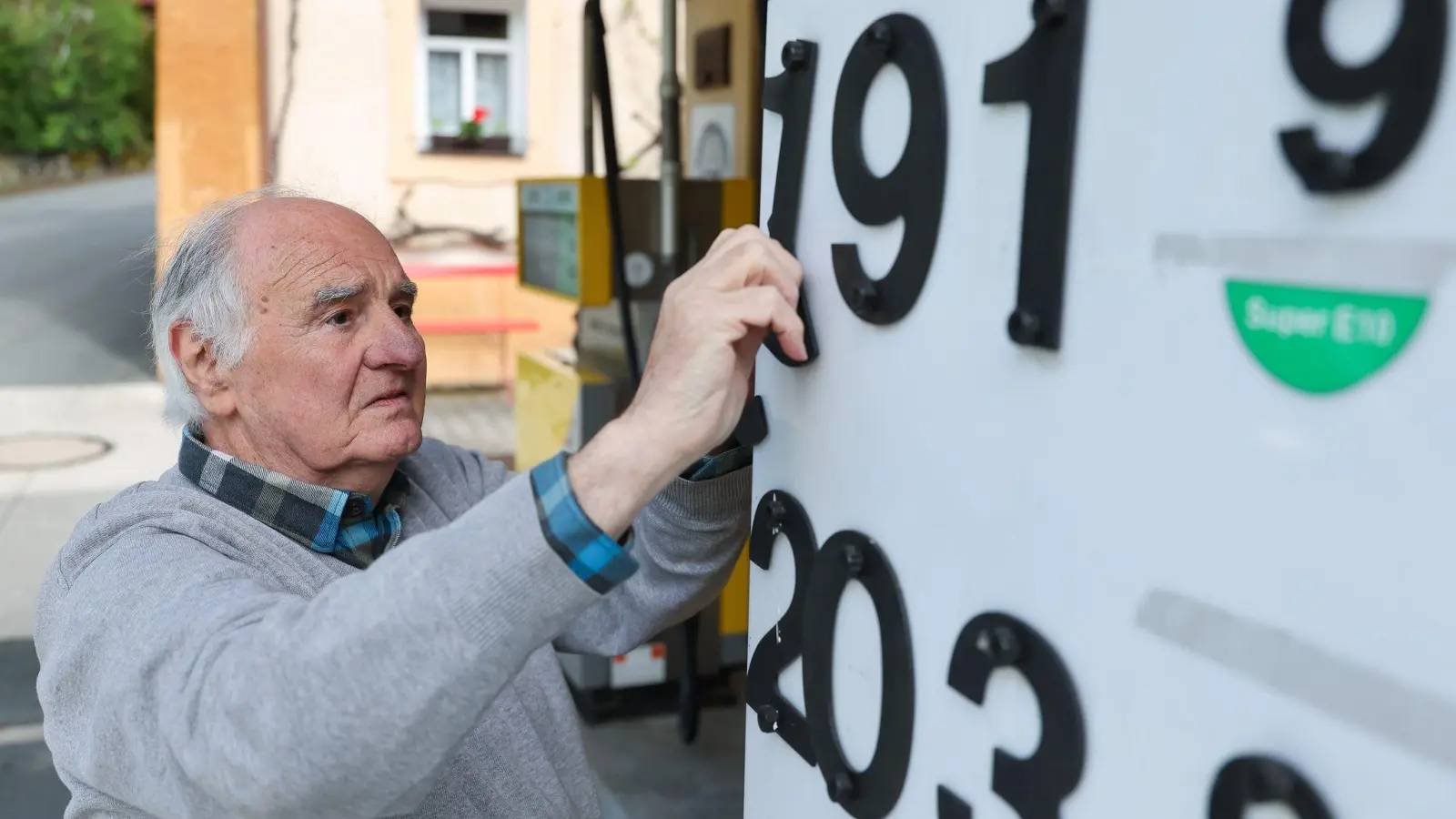 Herbert Brendel passt die Preisanzeige noch händisch an.  (Foto: Daniel Löb/dpa)