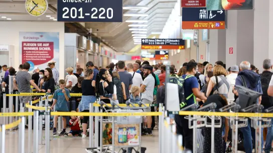 Passagiere stehen in einer Schlange von mehreren hundert Metern für die Sicherheitskontrolle am Flughafen Köln Bonn an. (Foto: Thomas Banneyer/dpa)