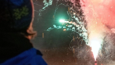Ein Junge betrachtet ein buntes Feuerwerk auf der Straße eines Dorfes. (Foto: Pia Bayer/dpa)
