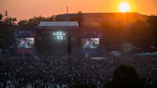 Die Sonne geht bei Rock im Park über der Mandora Stage und der Kongresshalle unter. (Foto: Daniel Vogl/dpa)