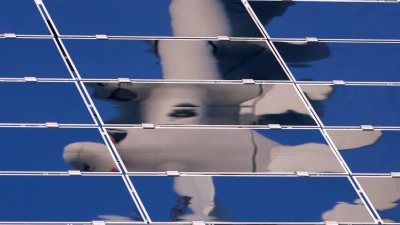 Ein Windrad spiegelt sich in einer Solar-Anlage. (Foto: Karl-Josef Hildenbrand/dpa)
