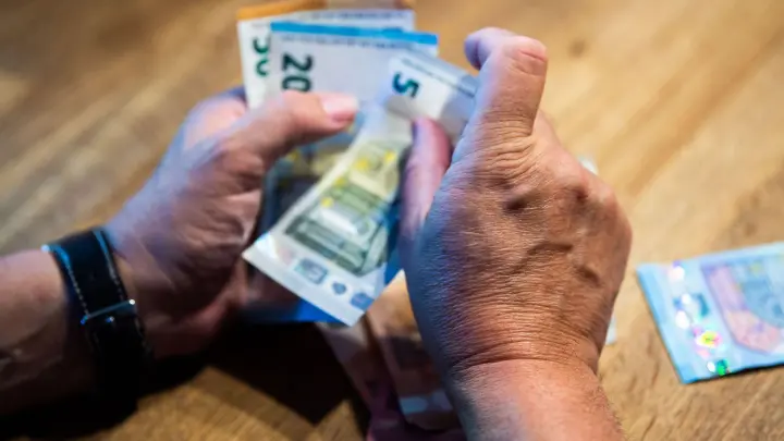 Ein älterer Mann zählt Geld an einem Tisch. (Foto: Lino Mirgeler/dpa/Illustration)