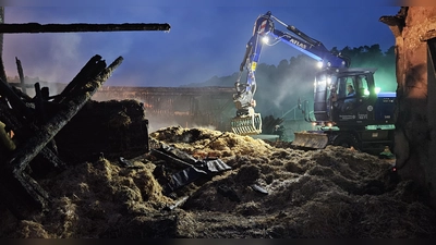 Bis tief in die Nacht dauert es, bis das mit Glutnestern durchsetzte Stroh abgetragen und zum Löschen auf eine Wiese verfrachtet ist. Ein Bagger des THW und mehrere Frontlader sind im Einsatz. (Foto: Wolfgang Grebenhof)