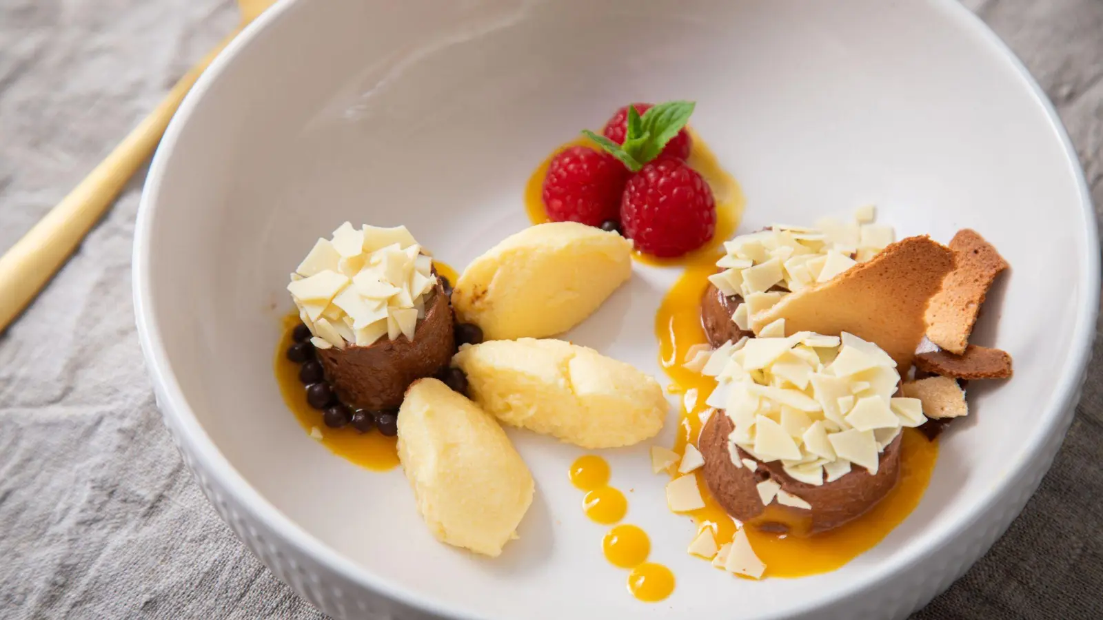 Dessert-Teller mit Schokoladen- und Mango-Mousse auf Mangopüree. Getoppt wird alles mit Eiswaffelsplittern, Schokoraspeln, Himbeeren und Minzblättern.  (Foto: Christin Klose/dpa-tmn)