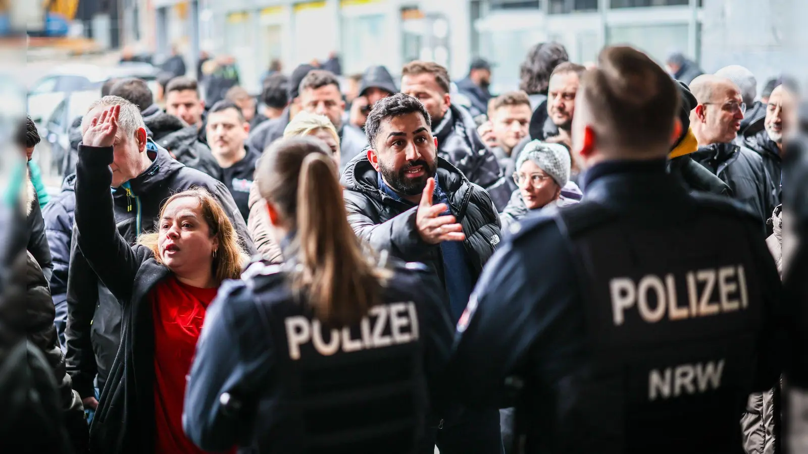 Aufgebrachte Kunden diskutieren vor der Sparkassenfiliale in Buer mit Polizeibeamten nach der Räumung des Vorraums der Filiale. (Foto: Christoph Reichwein/dpa)