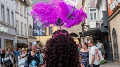 Eine Person mit Federkopfschmuck läuft während des Samba-Festivals durch die Innenstadt. (Foto: Daniel Vogl/dpa)