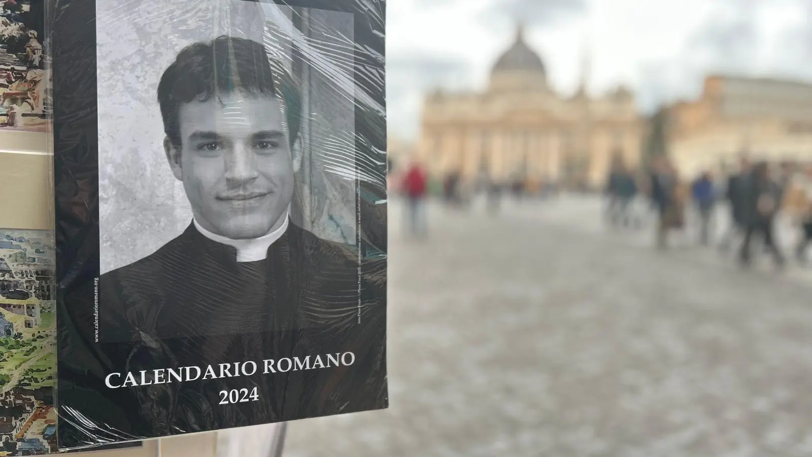 Der „Calendario Romano“ an einem Souvenirstand, im Hintergrund der Petersdom. (Foto: Christoph Sator/dpa)