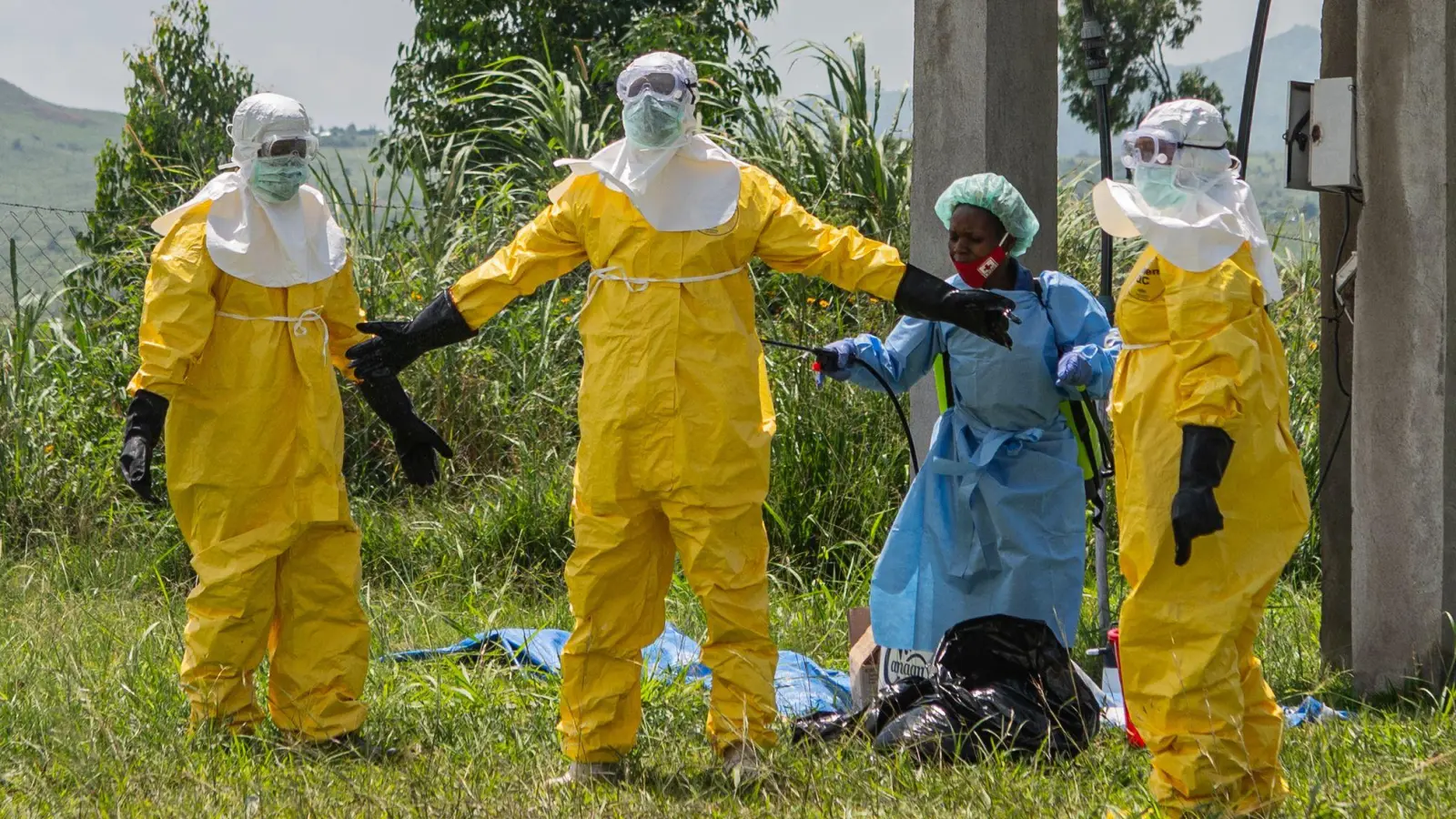 Mitarbeiter des Roten Kreuzes in Schutzkleidung desinfizieren sich. (Foto: Moses Sawasawa/AP/dpa)