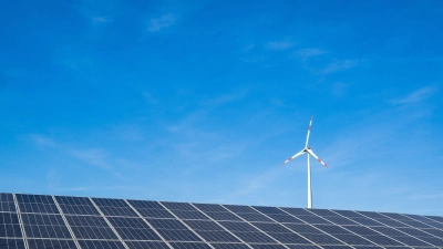 Ein Windrad hinter einem Solarfeld. Ab dem 1. Juli müssen Stromkunden die Förderung des Ökostroms nicht mehr über die Stromrechnung zahlen. (Foto: Peter Kneffel/dpa)