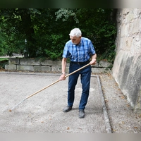 Karl Springer pflegt den Boule-Platz im Stadtgraben in Ansbach. Er muss aktuell immer wieder Löcher und Furchen mithilfe eines Rechens auffüllen. (Foto: Luca Paul)