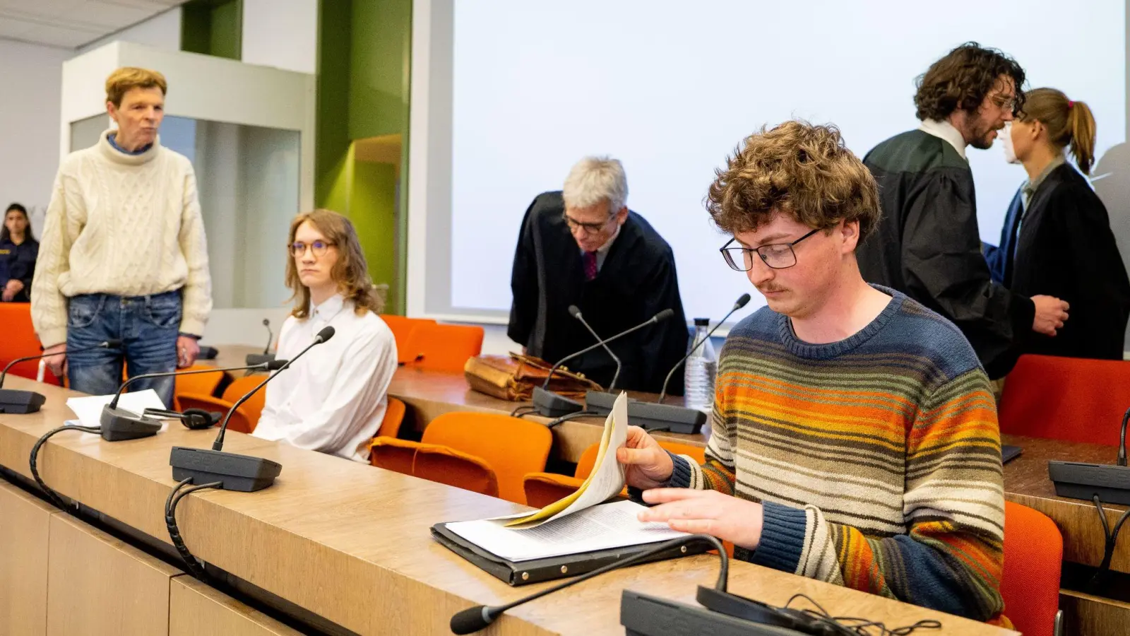 Die angeklagten Klimaaktivisten Michael Winter (l-r), Lukas Popp und Simon Lachner sitzen zum Prozessauftakt auf der Anklagebank. (Foto: Lennart Preiss/dpa)