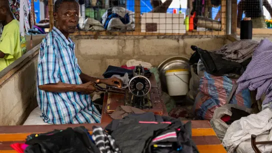Ein Mann arbeitet auf einem Markt in Ghanas Hauptstadt Accra, wo unter anderem Kleidung aus Europa verkauft oder weiterverarbeitet wird. (Foto: Christophe Gateau/dpa)