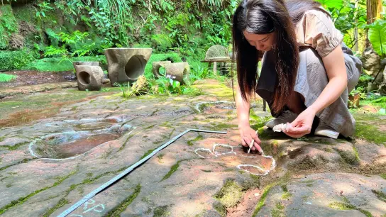 Eine Wissenschaftlerin im Forscherteam von Lida Xing untersucht die etwa 100 Millionen Jahre alte Dinosaurier-Fußabdrücke. (Foto: ---/Lida Xing Team/dpa)