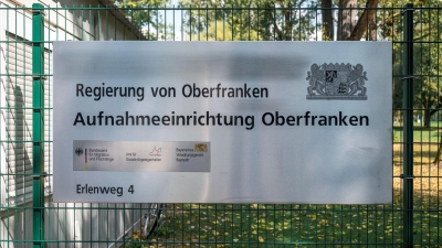 Ein Hinweisschild der Aufnahmeeinrichtung Oberfranken hängt am Zaun der Flüchtlingsunterkunft. (Foto: Daniel Vogl/dpa)