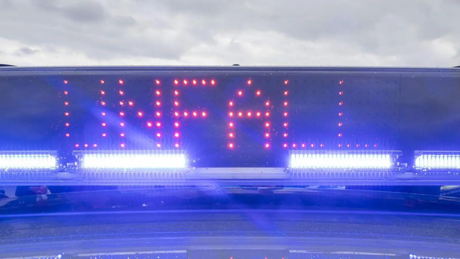 Ein Blaulicht auf dem Dach eines Polizeifahrzeugs mit der LED-Anzeige „Unfall”. (Foto: Daniel Karmann/dpa/Symbolbild)