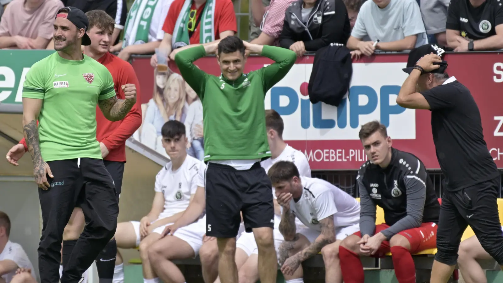 Freund und Leid direkt nebeneinander: Während Buchbacher die Fäuste ballen, herrscht bei Ansbach Entsetzen über ein weiteres Gegentor. Trainer Christoph Hasselmeier (langes grünes Shirt) hofft auf einen Lerneffekt aus der Heimnederlage. (Foto: Martin Rügner)