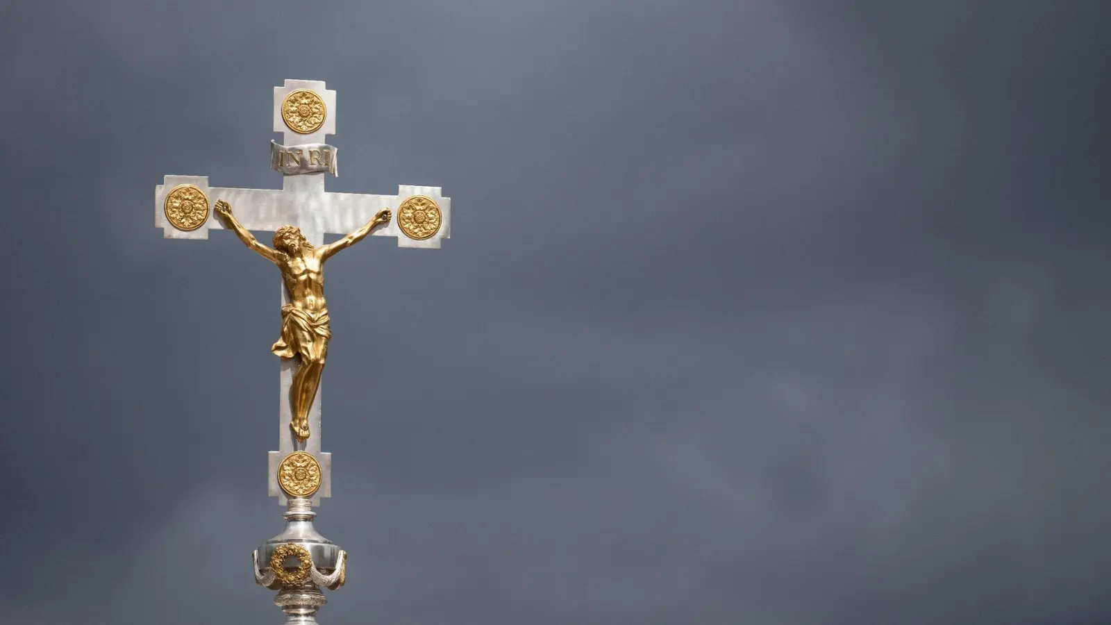 Dunkle Wolken über einem Kruzifix: Immer mehr Menschen nehmen Abstand von der Katholischen Kirche. (Foto: Marijan Murat/dpa)