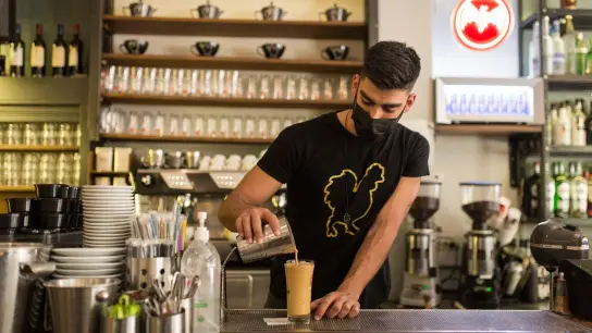 Ein Barista bereitet einen Kaffee in einem Coffee-Shop im Zentrum Athens zu. Laut Tourismusverband konnte die Tourismusbranche zum Saisonstart rund 50.000 Stellen nicht besetzen. (Foto: Socrates Baltagiannis/dpa)