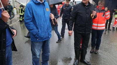 Markus Söder (CSU, l), bayerischer Ministerpräsident und Joachim Herrmann, bayerischer Innenminister (CSU, M), stehen am Rande einer überfluteten Straße. (Foto: Karl-Josef Hildenbrand/dpa)