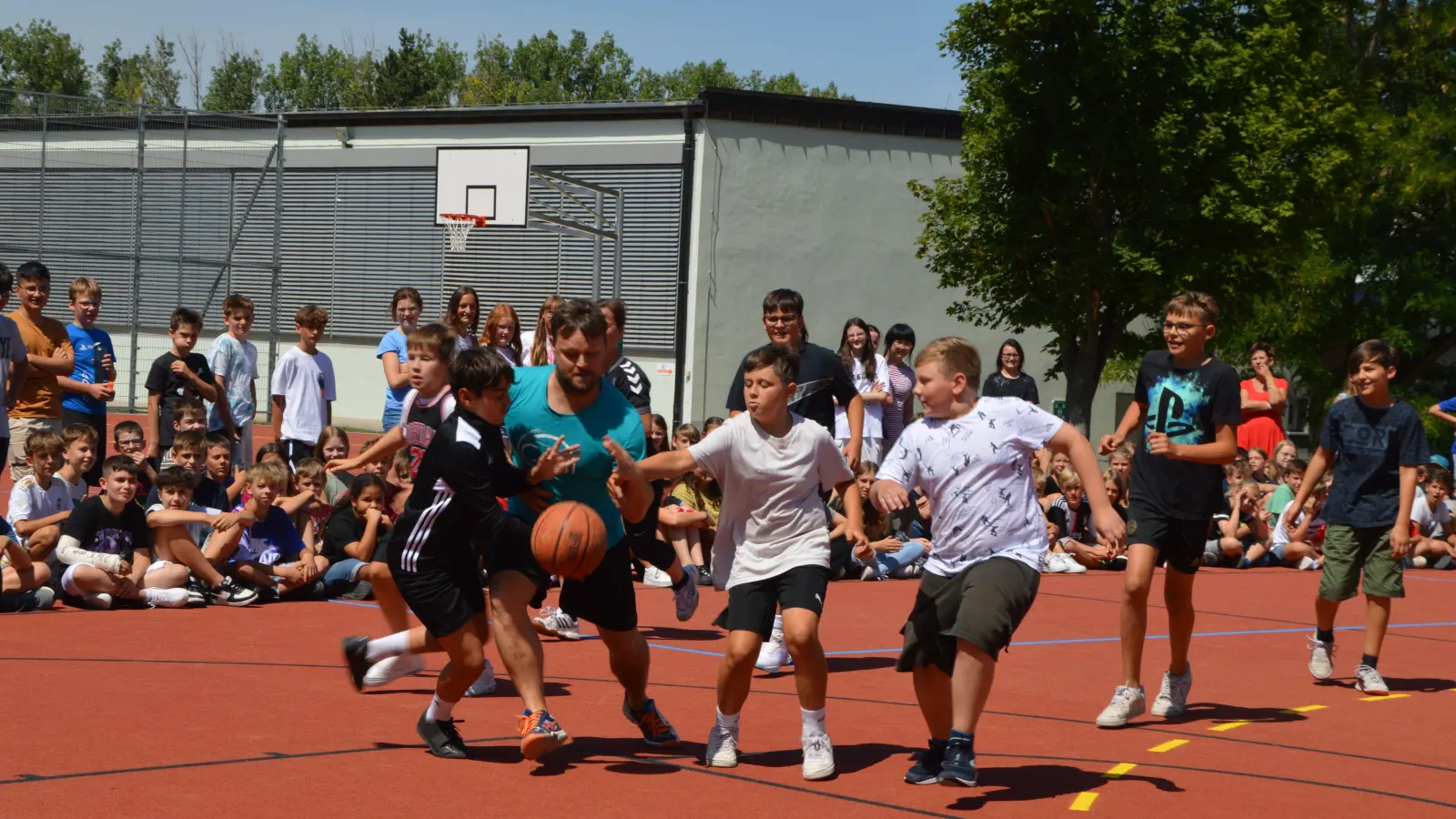 Das Ein-Mann-Lehrerteam Xaver Frühwirth (in blau) hat es zu Beginn der Partie gegen die Schülermannschaft wahrlich nicht leicht, auch wenn sich Frühwirth als begnadeter Dribbel-König präsentiert. (Foto: Johannes Zimmermann)