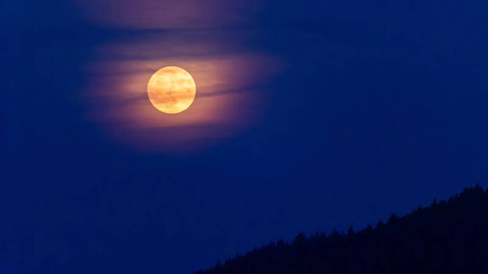 Der Rauch von den Waldbränden in Kanada lässt den Vollmond orange-rötlich erscheinen.  (Foto: Philipp von Ditfurth/dpa)