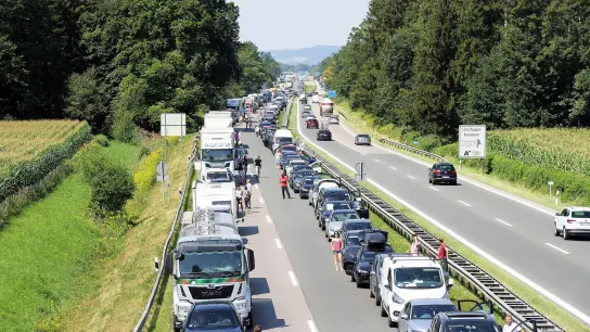 Die Autofahrer haben eine Rettungsgasse gebildet und stehen neben ihren Fahrzeugen auf der Autobahn. (Foto: Josef Reisner/dpa)