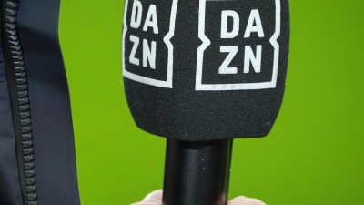 Chef-Trainer Kovac von Wolfsburg hält vor dem Spiel ein Mikrofon mit dem Logo des TV-Senders DAZN. (Foto: Soeren Stache/dpa/Archivbild)
