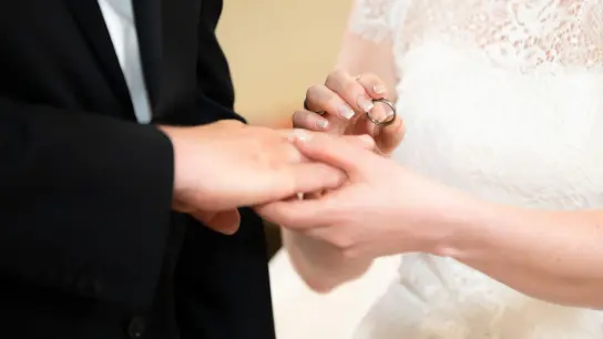 Ein Brautpaar steckt sich während der Trauung in der Kirche die Ringe an. Der Hochzeitsstau nach der Coronakrise scheint gebrochen. (Foto: Silas Stein/dpa)