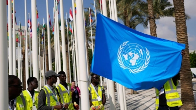 Die Flagge der Vereinten Nationen wird vor dem UN-Klimagipfel COP28 aufgehangen. (Foto: Rafiq Maqbool/AP/dpa)
