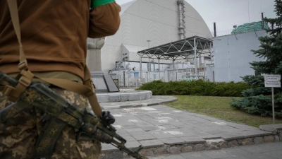Ein ukrainischer Soldat steht vor dem Sarkophag, der den explodierten Reaktor im Kernkraftwerk Tschernobyl abdeckt. (Foto: Efrem Lukatsky/AP/dpa)