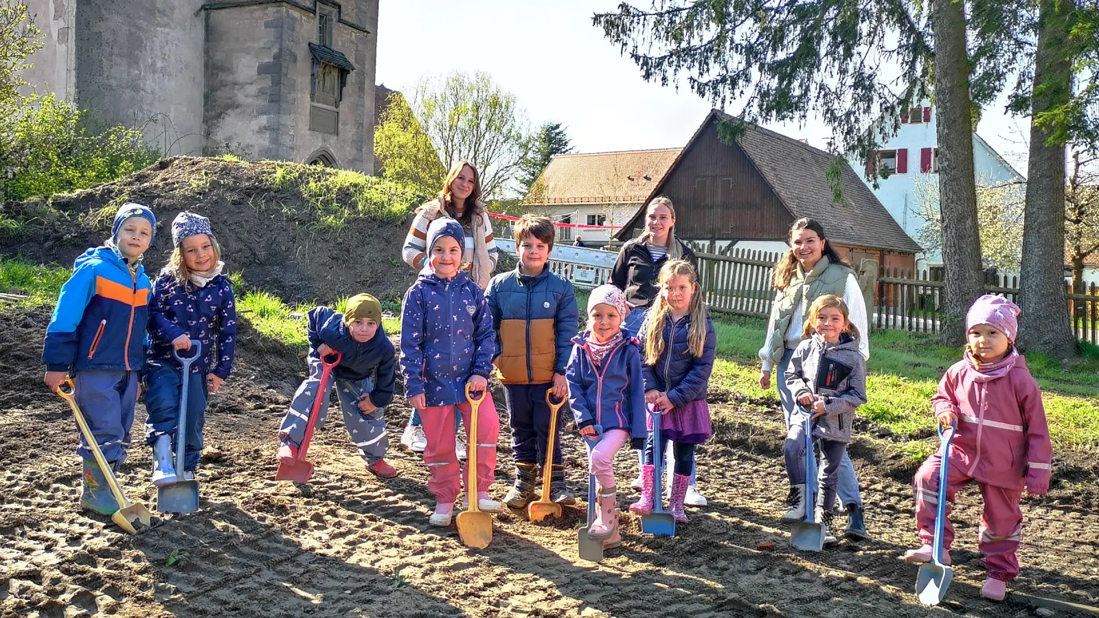 In seinem Jubiläumsjahr wird der Kindergarten in Kloster Sulz auch erweitert. Wo das neue Gebäude entstehen soll, schwangen einige der Kleinen schon einmal symbolisch den Spaten. Das Foto zeigt sie mit (von links) Leiterin Daniela Bäuerlein und den Erzieherinnen Milena Albig und Lara Wieczorek. Im Hintergrund sind Teile der alten Klosteranlage zu sehen, die als Stammdomizil weiterhin genutzt wird. (Foto: Jürgen Binder)
