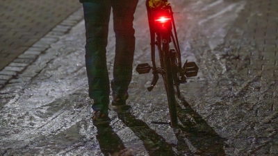 Ein Mann schiebt sein Fahrrad auf einer vereisten Straße. (Foto: Armin Weigel/dpa)