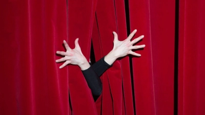 Die Hände einer Schauspielerin auf einem roten Vorhang. (Foto: Sebastian Kahnert/dpa-Zentralbild/dpa/Symbolbild)