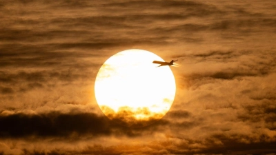 Der Tag geht zu Ende: Ein Flugzeug fliegt vor der untergehenden Sonne über Frankfurt am Main. (Foto: Boris Roessler/dpa)