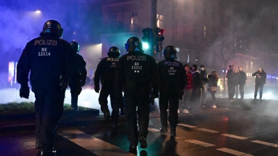 Polizeibeamte gehen während der Silvesternacht in Neukölln über eine Straße. (Foto: Sebastian Christoph Gollnow/dpa)